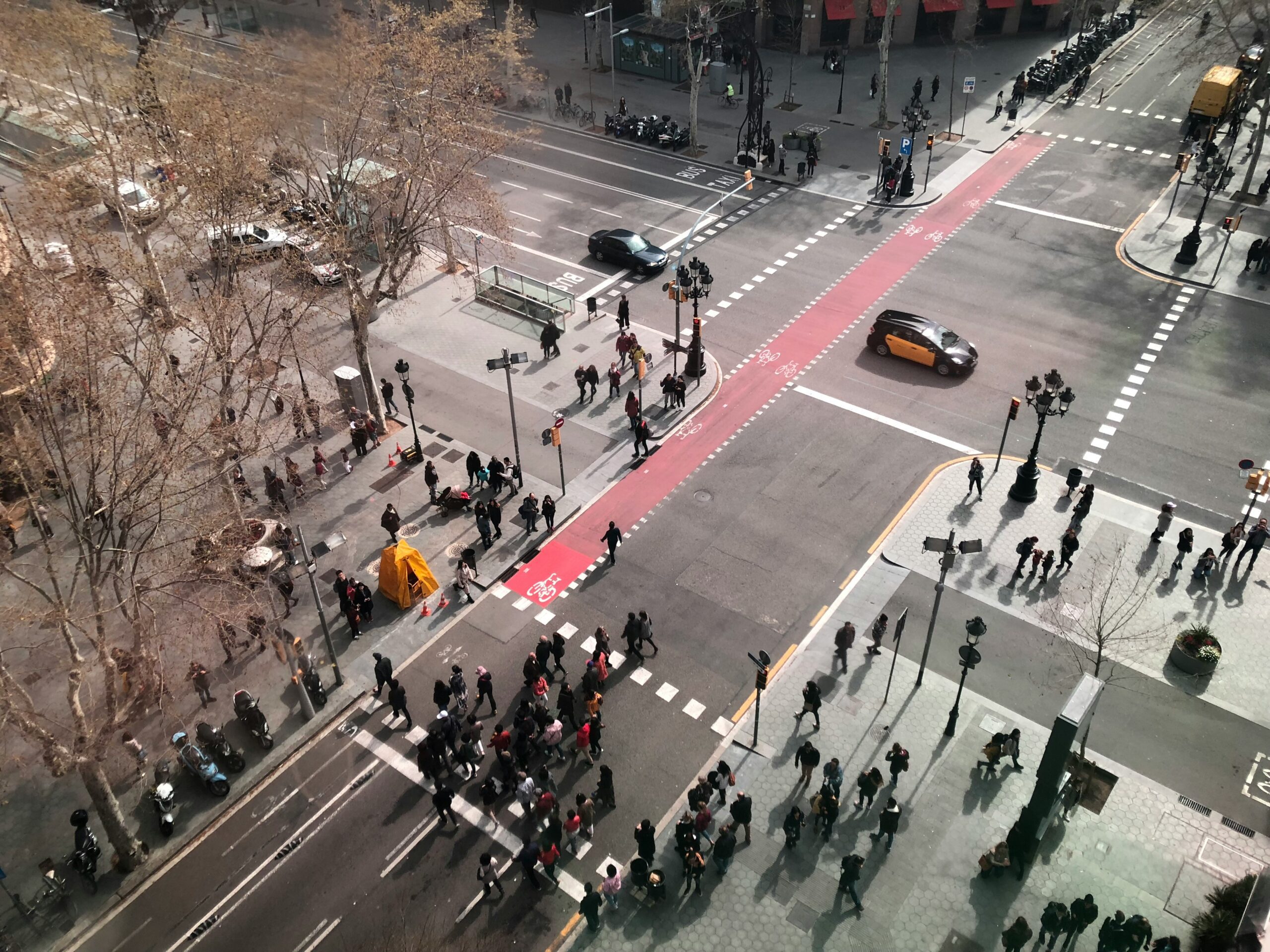 A bustling street scene with pedestrians walking and cars navigating through traffic.