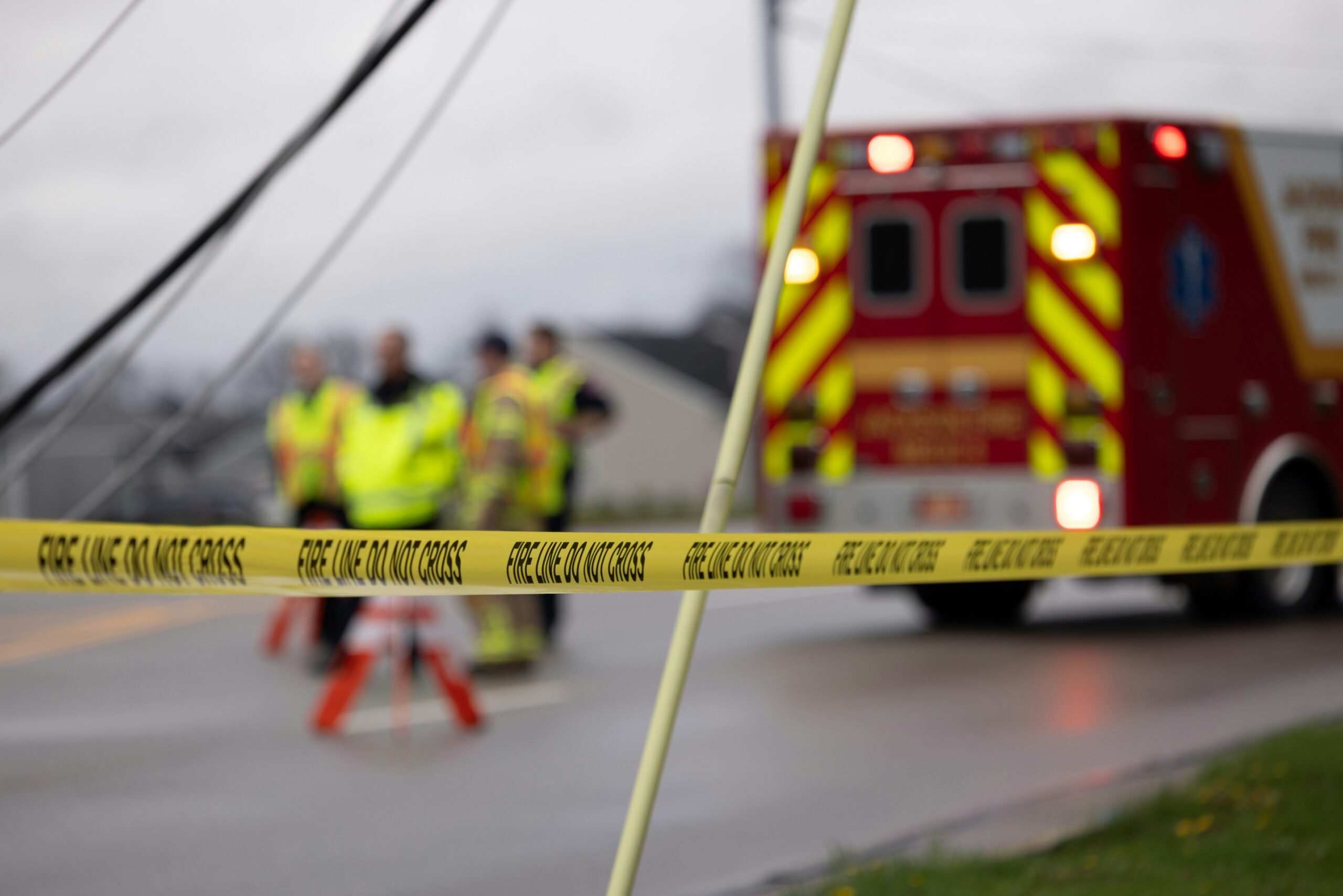 A red ambulance parked near yellow caution tape, indicating a scene of emergency or potential hazard.
