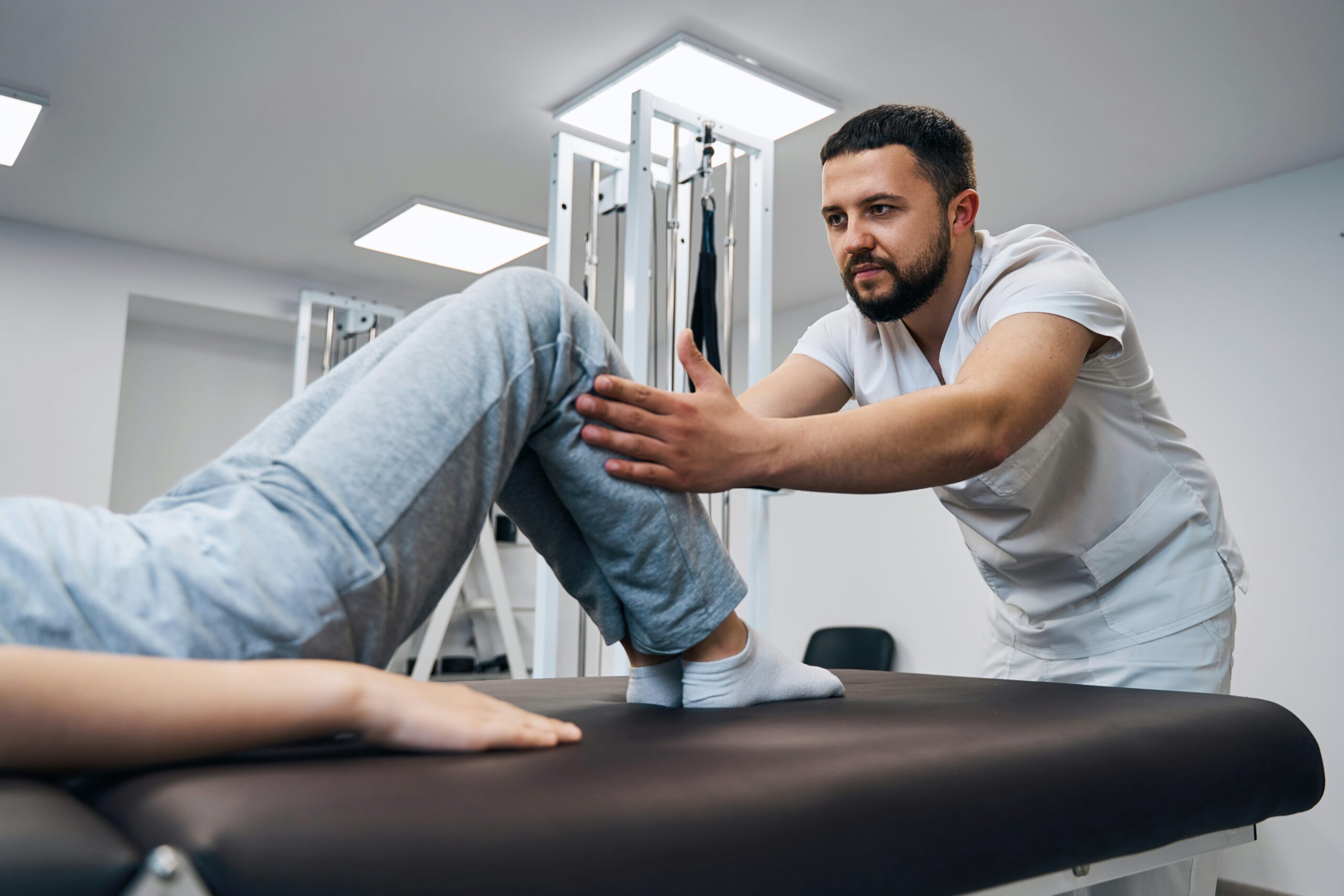 A man is having his leg examined by a doctor in a clinical setting.