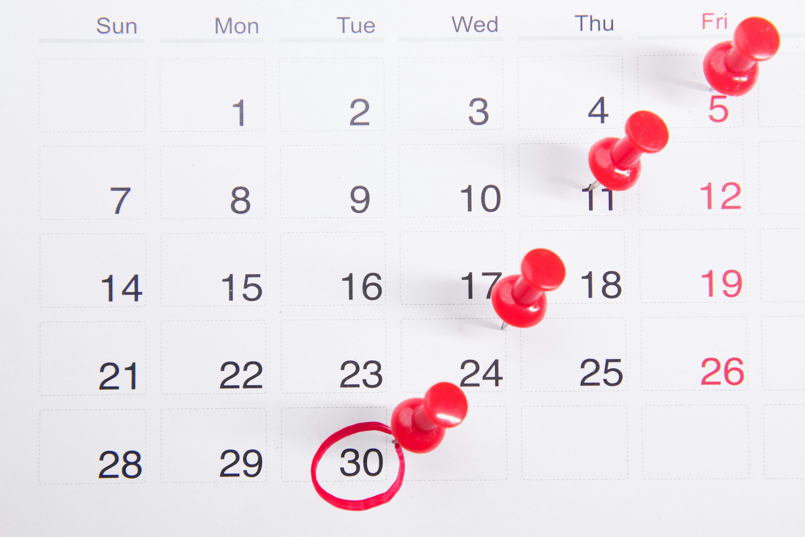 A calendar page marked with red pins indicating specific dates for important events or reminders.