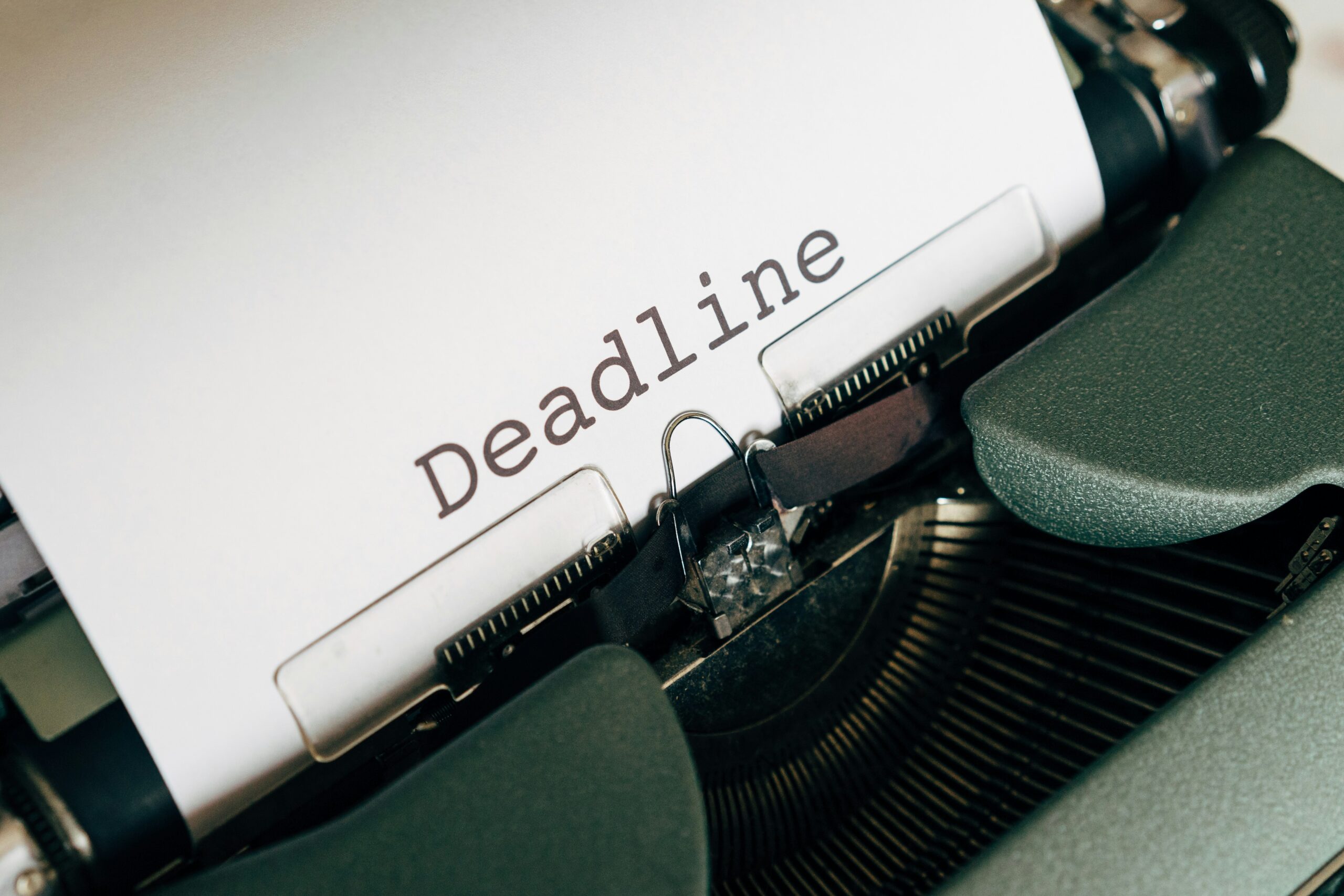 Typewriter with a sheet of paper displaying the word "deadline," symbolizing urgency and time constraints.