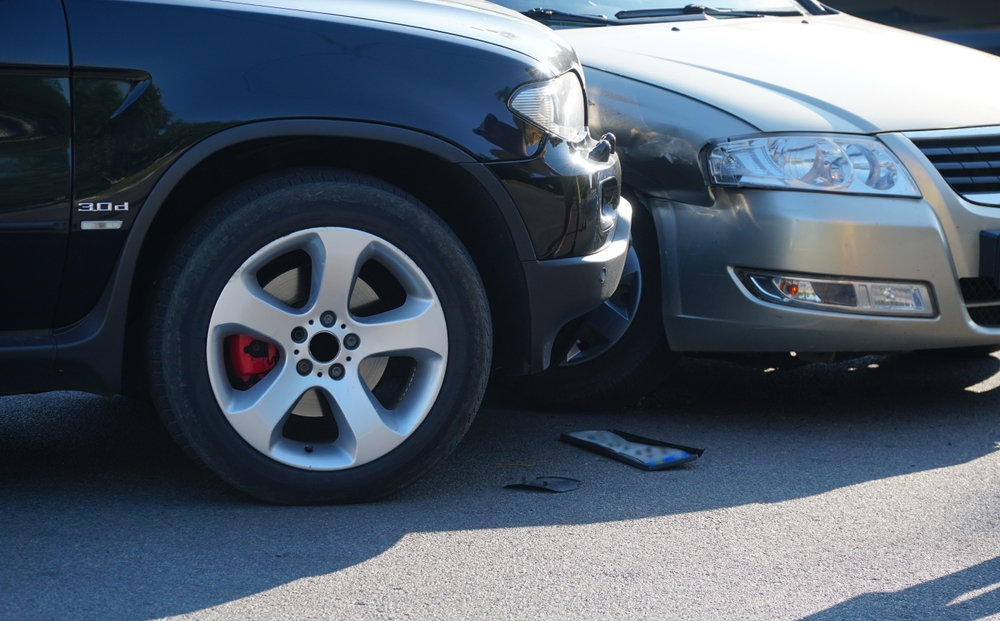 Two cars collided front-to-side with damaged bodywork and debris on the ground