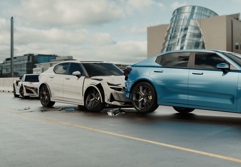 White car with a crushed front end stopped behind a blue car on a highway